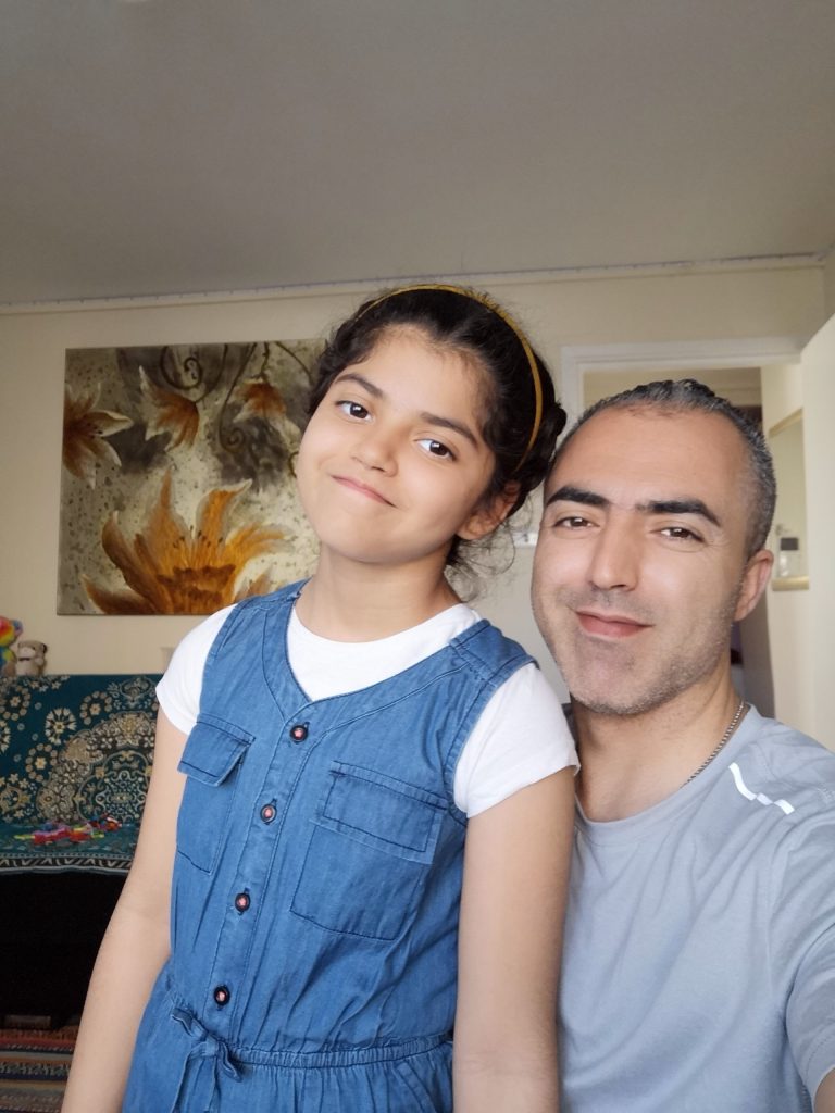 Dad and daughter smile for the camera in their living room. 