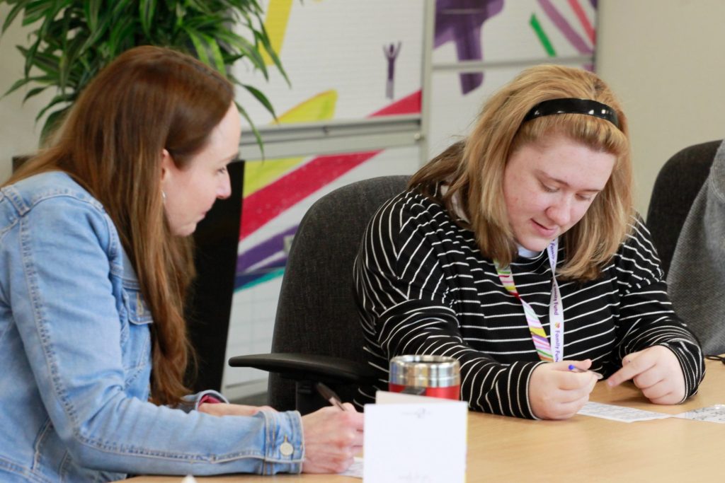 A staff member supporting an intern at a desk in an office