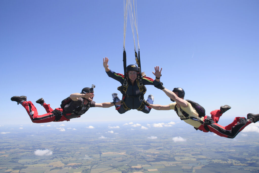 A group of skydivers free falling with the ground far below.