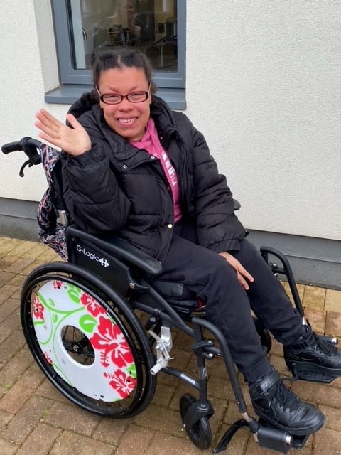 Young woman in a wheelchair waving at the camera