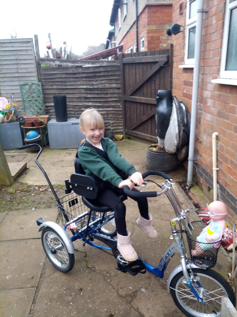 Girl rides on specialist tricycle