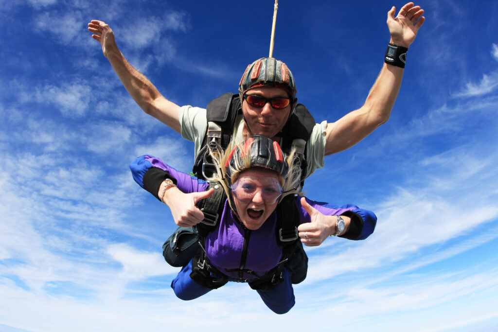 A tandem skydive. The woman has both thumbs up.