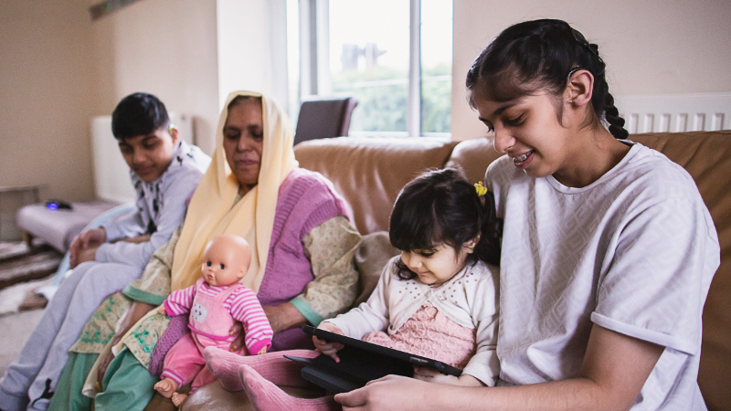 A family sits together looking at their iPad