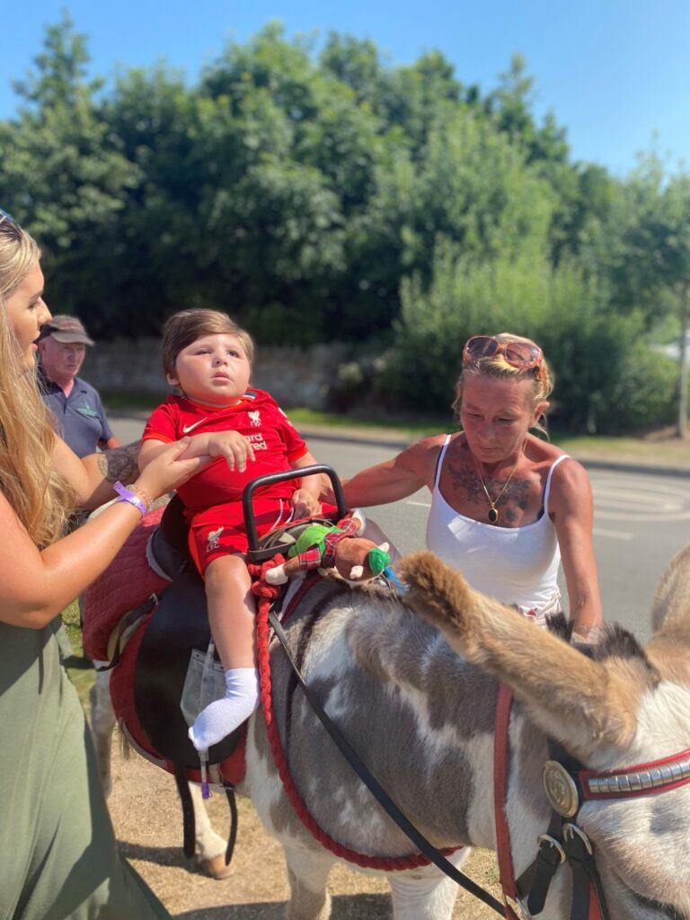 Leo riding a donkey with the support of his family.