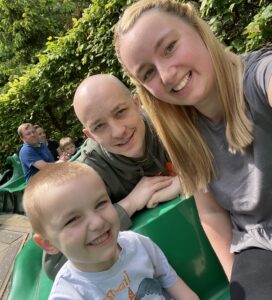 Mum and son sit on front of a ride smiling at the camera, with dad sat behind them.