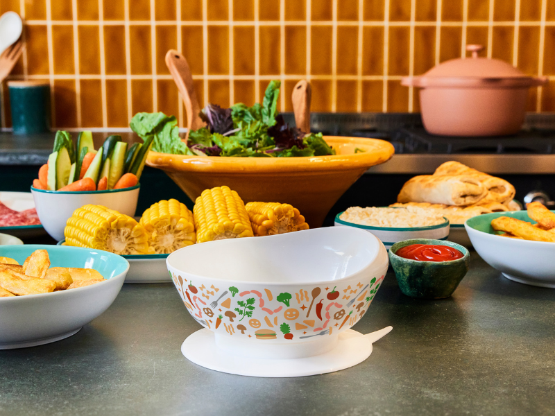 The limited edition Family Fund and McCain scoop bowl on a kitchen top surrounded by plates of party food