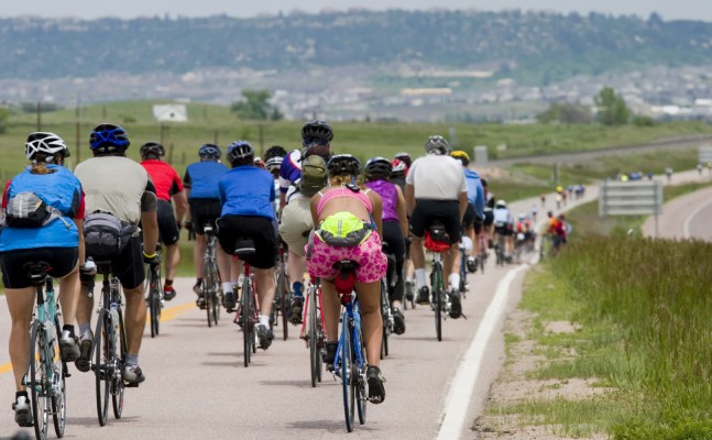 A large group of cyclists on a road biking into the distance