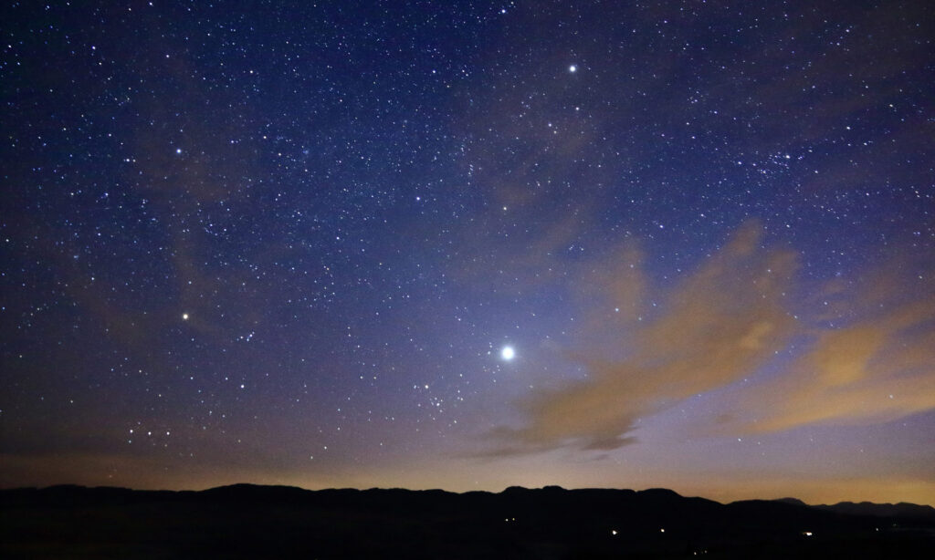 A photo from a mountain top of a star filled night sky