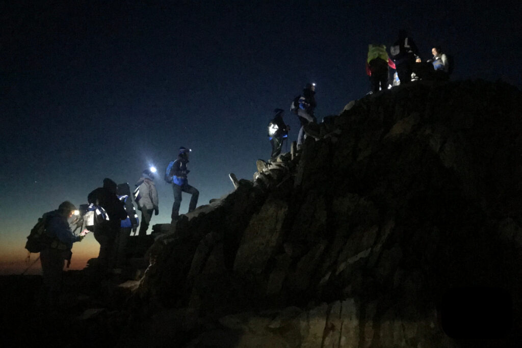 A group of hikers climbing mount Snowdon at night time with torches