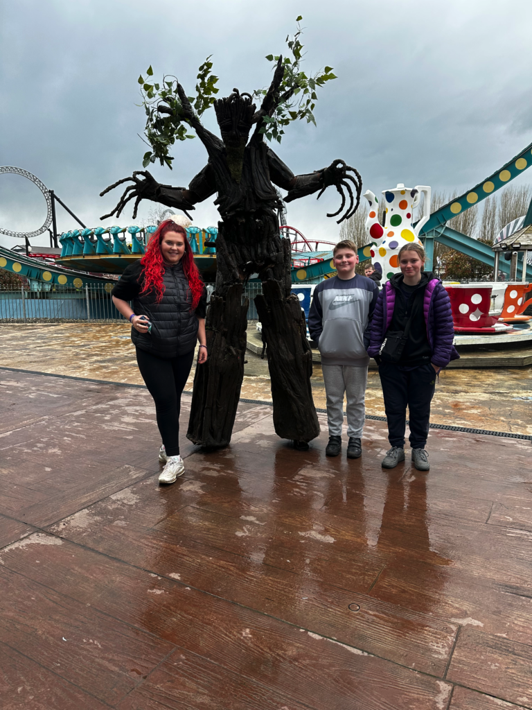 Three teenagers are standing outside, next to a statue, smiling at the camera