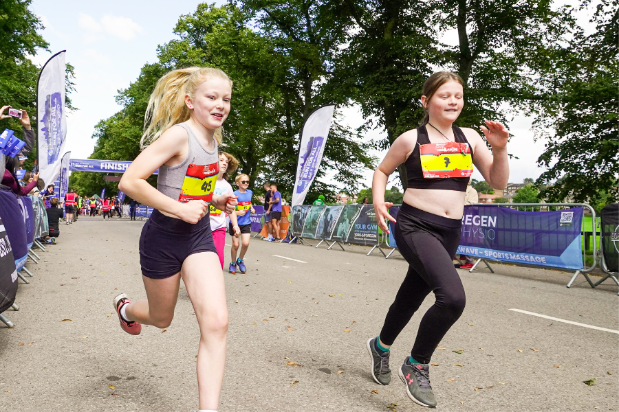 Two girls wearing running gear compete in the York Mini and Junior run