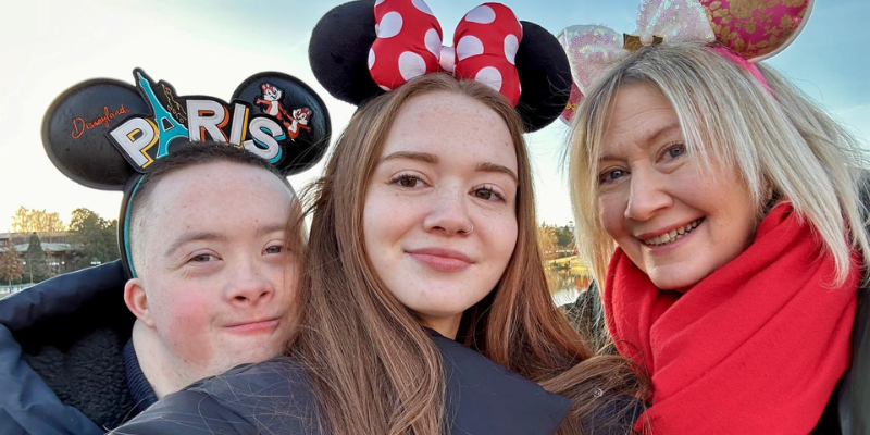 Josh, his sister and mum are all huddled together for a selfie. They all have Disney's Mickey and Minnie Mouse ears on their heads.