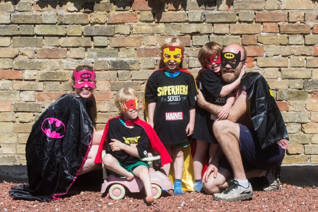 A family sitting together outside in various superhero costumes