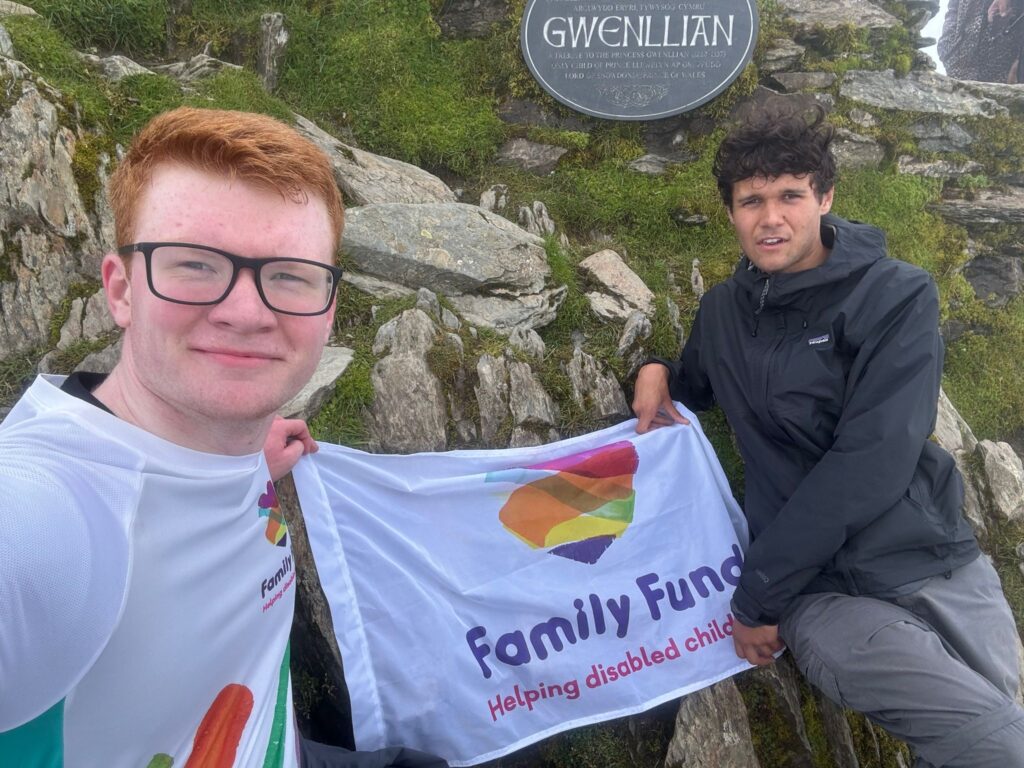 Climbers with Family Fund flag at the top of Snowdon during the UK 3 Peaks challenge