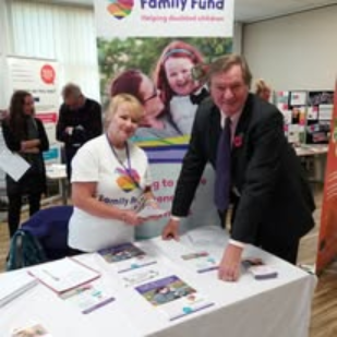 Elaine at a Family Fund event display with branded materials set up for attendees.