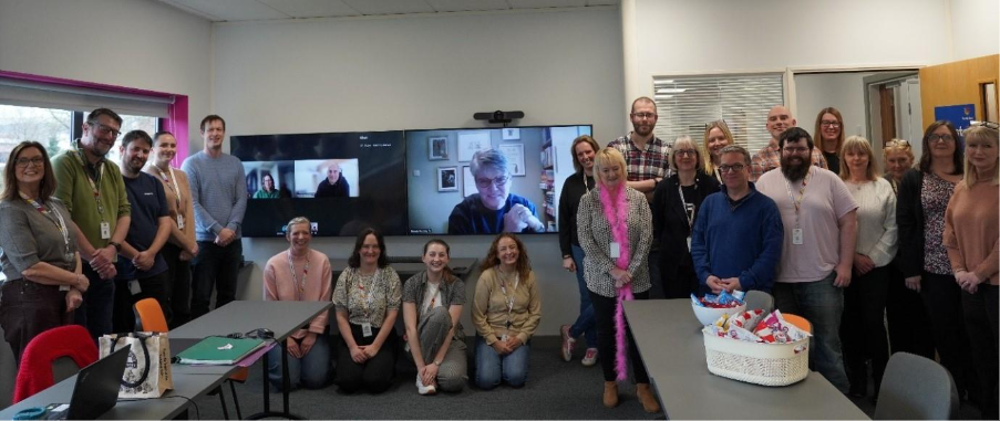 Elaine standing with colleagues at her leaving celebration, smiling together for a group photo.