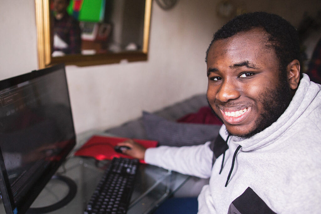 Young man smiles at camera while on computer