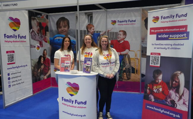 Three women standing around a Family Fund podium surrounded by Family Fund posters.