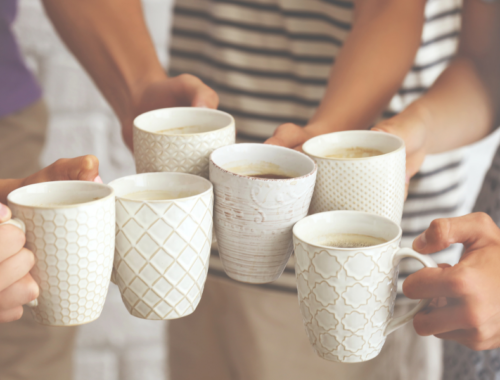 Coffee mugs being clinked together in celebration at a coffee morning