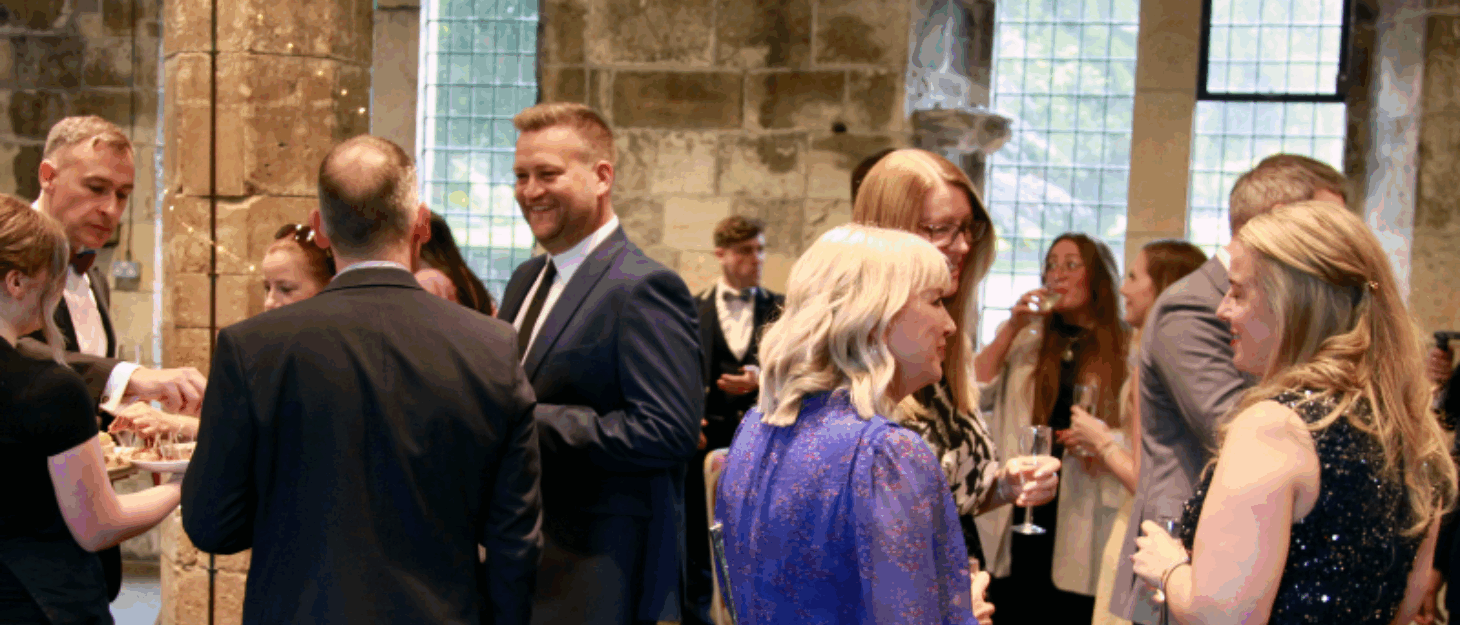 A group of people in evening dress are smiling and talking together