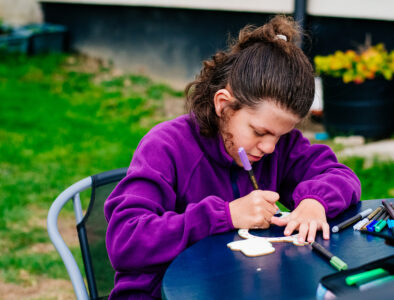 A girl in a purple jumper writing a card