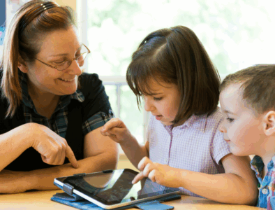 A mum with two children sitting at a table and looking at a tablet together