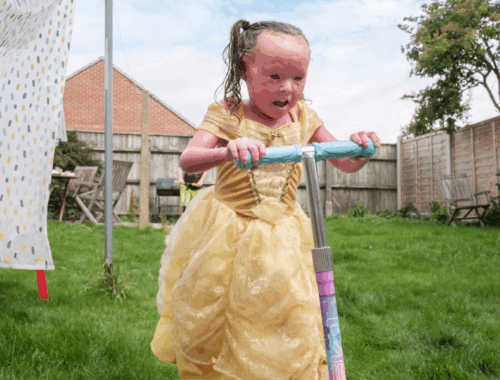 A young girl riding a scooter in a garden.