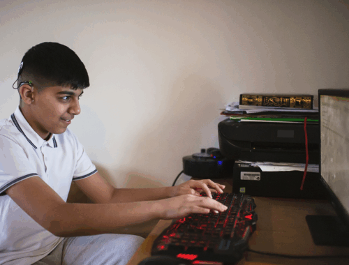 A young boy typing on a computer.
