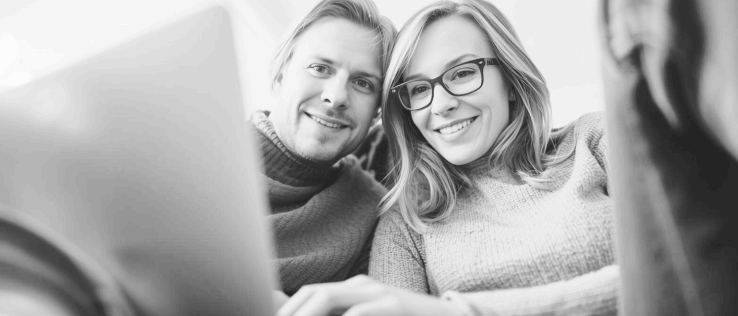 a grayscale image of a man and woman looking at a laptop screen