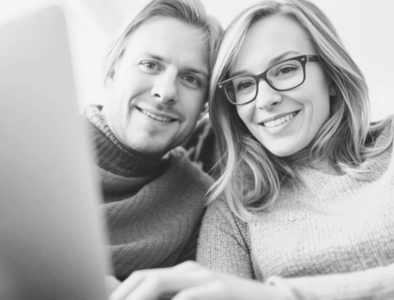 a grayscale image of a man and woman looking at a laptop screen