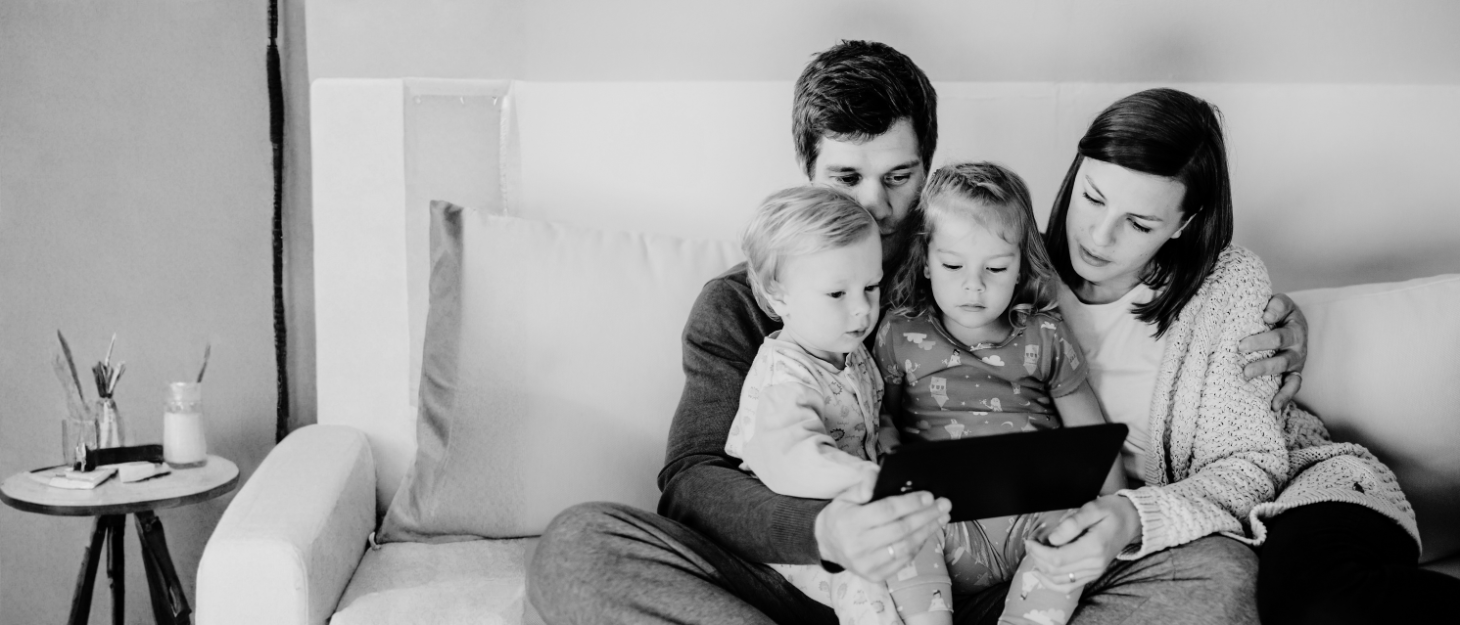 a family sitting on a sofa looking at a tablet