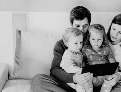a family sitting on a sofa looking at a tablet