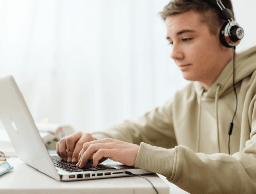 A young man wearing headphones looking at a laptop