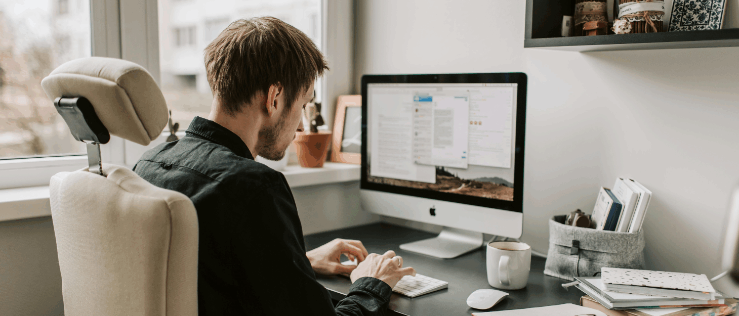 A young man sitting at a computer tapping on a keyboard