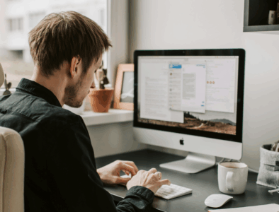 A young man sitting at a computer tapping on a keyboard