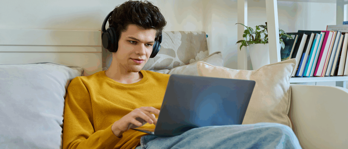 A young man say on his bed using a laptop