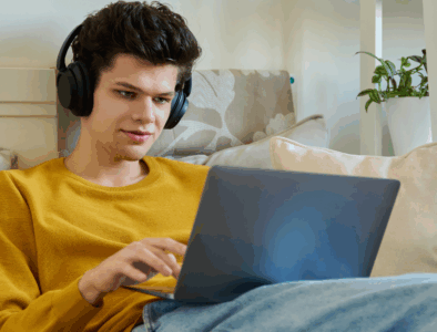 A young man say on his bed using a laptop