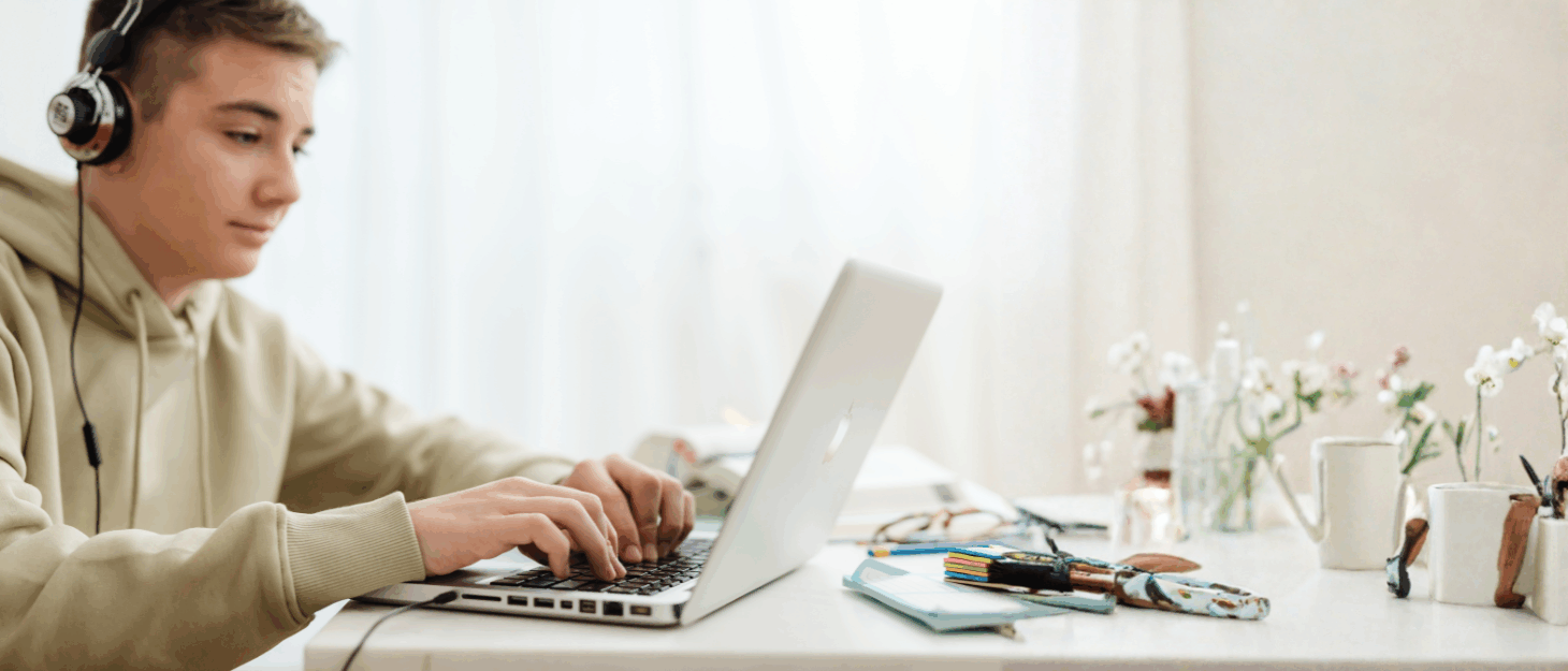 A young man wearing headphones typing on a laptop