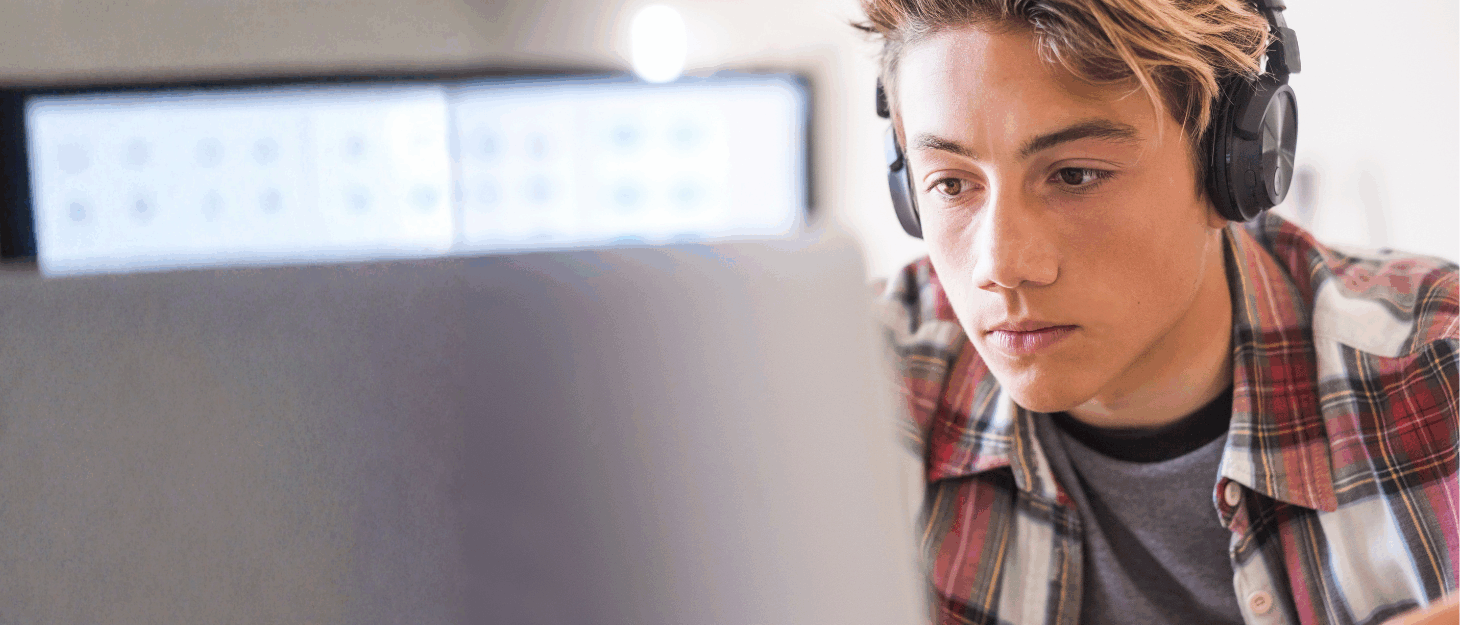 A young man wearing headphones looking at a computer screen