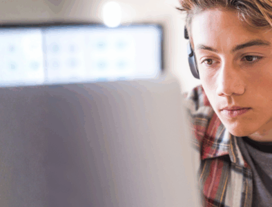 A young man wearing headphones looking at a computer screen