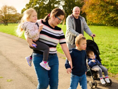 two adults with three children, one being carried and one in a pushchair