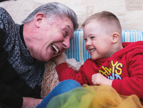 Joyful child playing on the sofa with a member of his family
