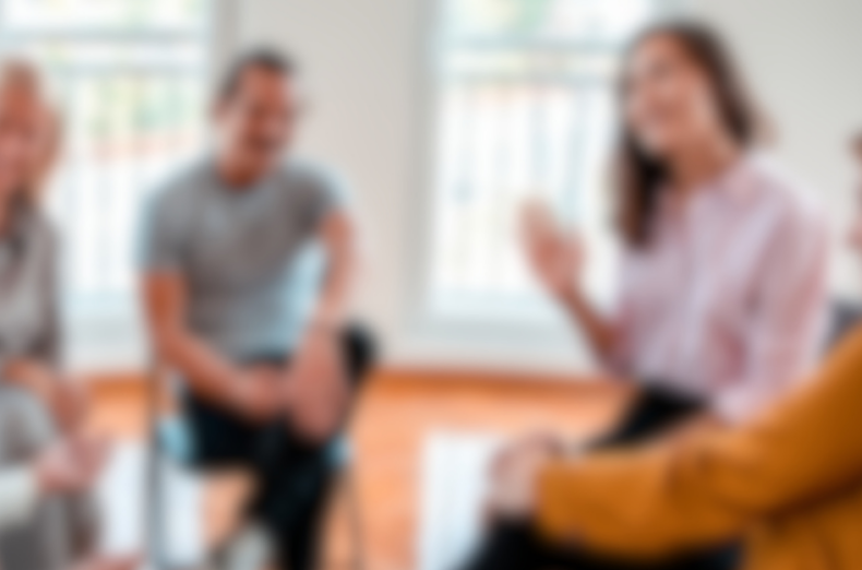 a blurred image of a group of adults sat chatting