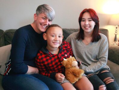 A mum sat on the sofa with her son and daughter