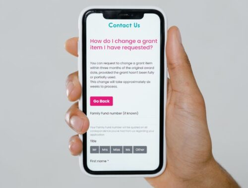 A hand holding a smart phone with the Family Fund change grant item online form open on the screen