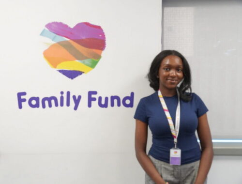 Crystal, a young female work experience student, stands in front of a Family Fund logo
