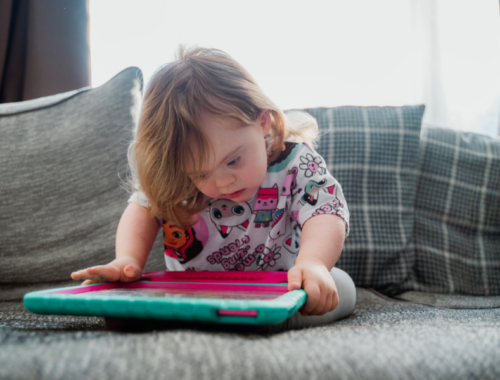 a young child sat playing on a tablet