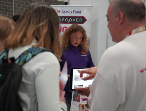 a busy event with a family fund staff member using a tablet