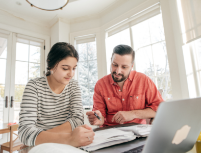 Parents looking at books and a laptop