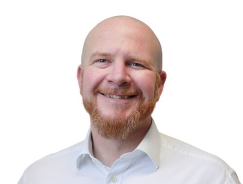 A man wearing a white shirt with a short ginger beard